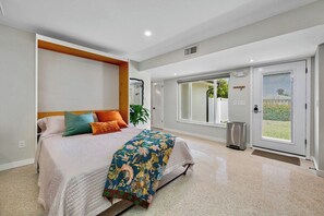 A bedroom with a bed, a bedside table, a window, and a door. - Hot Tub | Private Home | Ping Pong | Mins to Beach (Largo)