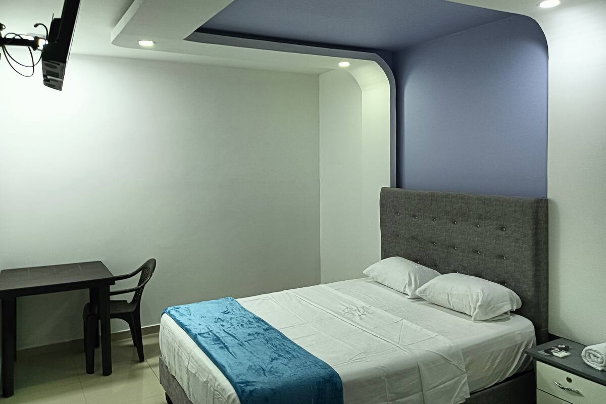 A bedroom with a bed, a desk, and a chair.