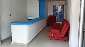 A reception area with a blue counter, a laptop, and a red sofa. - Hotel Pasarela Cali (Cali)
