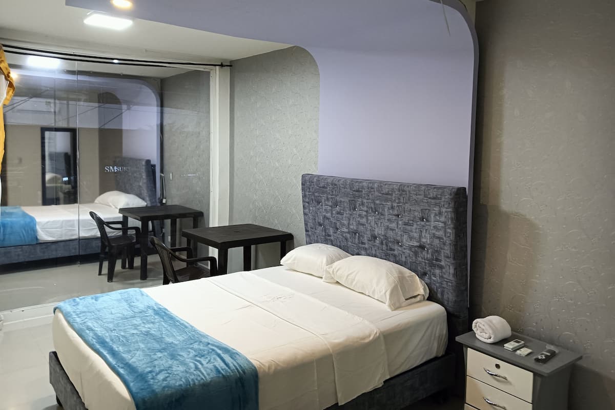 A modern hotel room with a bed, a desk, and a chair.