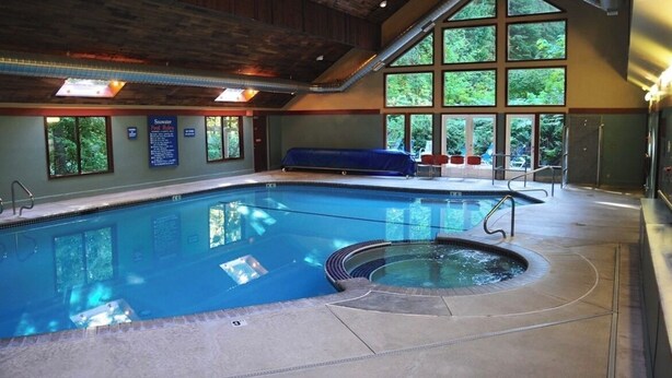 An indoor swimming pool with a hot tub, large windows, and a covered seating area. - Mountain Retreat near mt Baker, cozy 1bedroom Condo w/ Pool, Hot Tub, Crib, wifi (Deming)