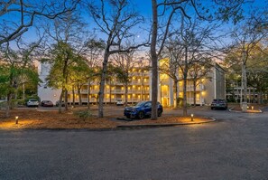 A hotel with multiple floors, a parking area, and trees.