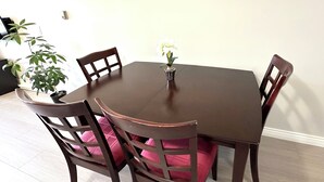 Ein Esstisch mit vier Stühlen, einer Topfpflanze und einer Blumenvase.