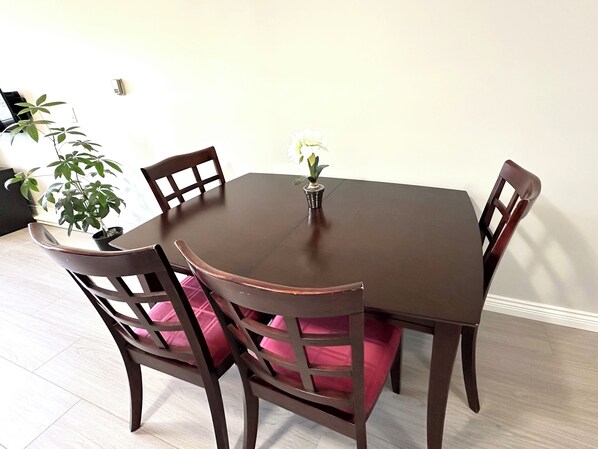 Una mesa de comedor con cuatro sillas, una planta en maceta y un jarrón con flores.