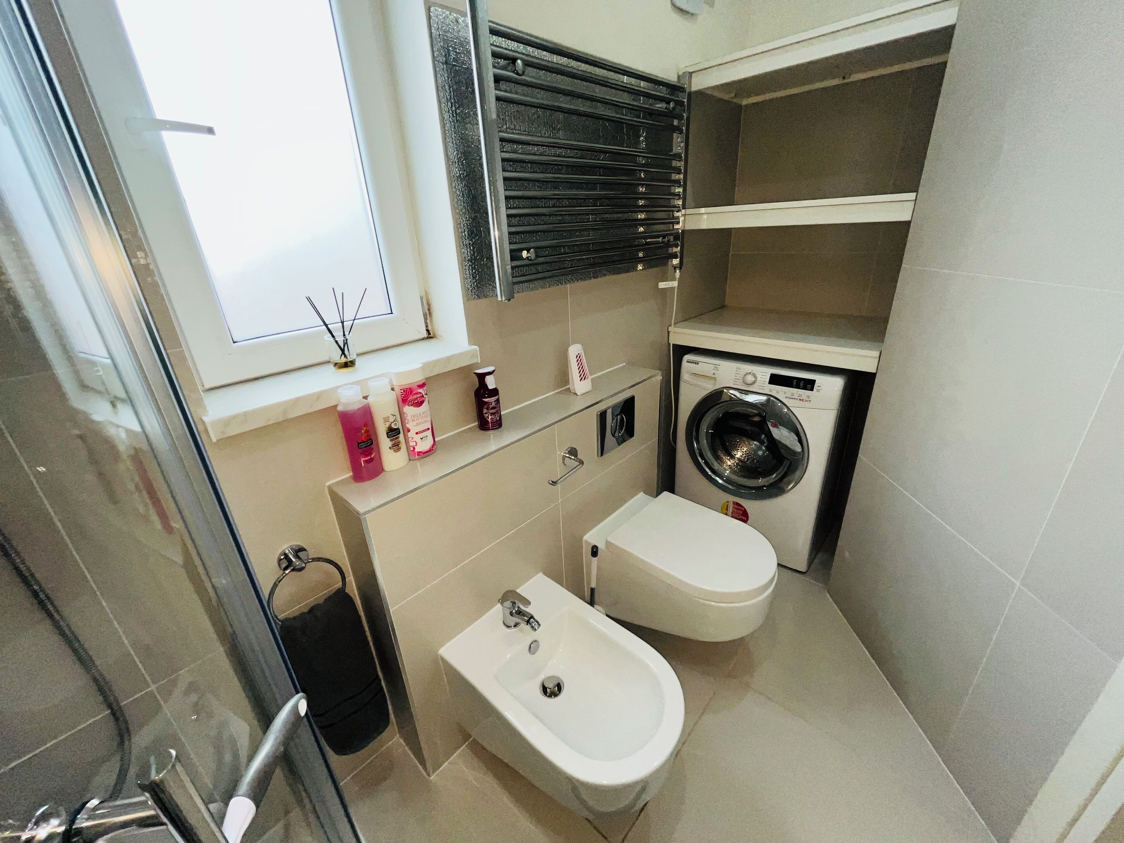 Un baño pequeño con inodoro, bidé, lavadora y ventana con vistas.