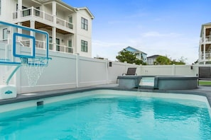Piscina com aro de basquete, fonte de água e cerca branca.