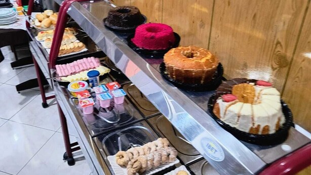 Buffet com diversos produtos de panificação, incluindo donuts, pastéis e bolos.