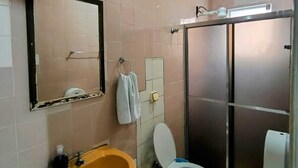Casa de banho com lavatório, sanita, espelho e cabine de duche.