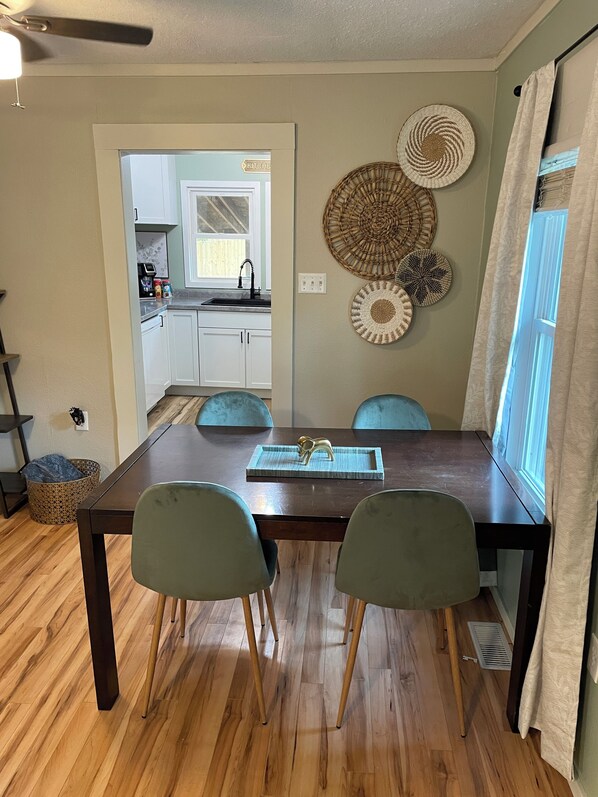 Un comedor con una mesa de madera, dos sillas y una cocina al fondo.