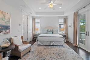 A bedroom with a large bed, a ceiling fan, a view through a window, and a wicker chair. - Time to Wine Down... 6 Bikes and 6-Seater Golf Cart, Heated Resort Pools, Pickleball Courts!!! (Santa Rosa Beach)