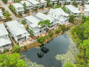 A residential area with multiple two-story houses, a small pond with lily pads, and surrounding greenery. - Time to Wine Down... 6 Bikes and 6-Seater Golf Cart, Heated Resort Pools, Pickleball Courts!!! (Santa Rosa Beach)
