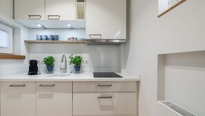 Eine moderne Küche mit weißen Schränken, einer Edelstahl-Dunstabzugshaube und einer eingebauten Spüle.