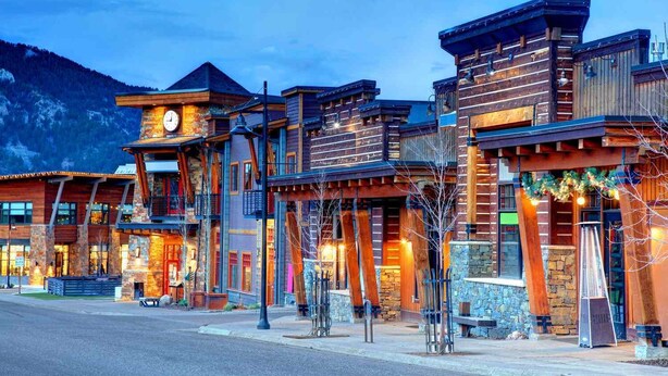 A multi-story wooden building with a clock tower, stone accents, and outdoor seating areas. - Hideout in the Mountains HOT TUB and River access (Gallatin Gateway)