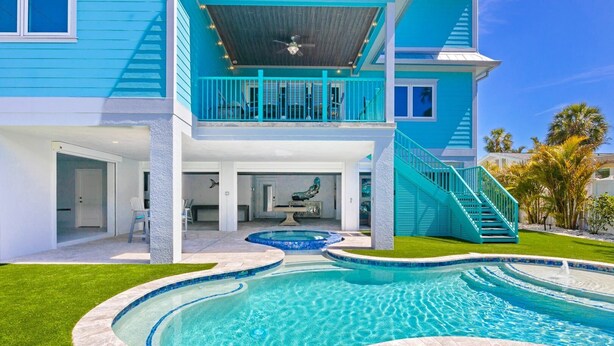 Una casa a due piani con piscina, un portico coperto e una scala che conduce al piano superiore.