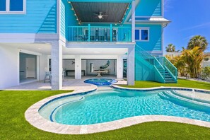 A two-story house with a swimming pool, a covered patio, and a staircase leading to the upper level. - Coral Reef: 50ft to Beach, Games Galore, Rooftop Deck, Pool, Spa by Anna Maria Life Vacation Rentals (Anna Maria)