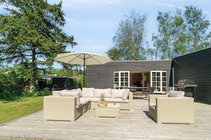 Eine Außenpatio mit Korbmöbeln, einem Tisch und einem Grill.