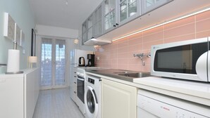 Une cuisine moderne équipée d’un lave-linge, d’un lave-vaisselle, d’un four à micro-ondes et d’une machine à café.