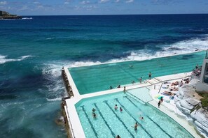 Ein großer Außenpool mit klarem, blauem Wasser, umgeben von Felsklippen und Blick auf den Ozean.