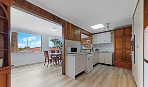 A kitchen with wooden cabinets, a microwave, a dishwasher, and a dining area with chairs and a table.