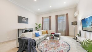 A living room with a sofa, coffee table, TV, and curtains.