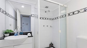 A bathroom with a white sink, a glass shower enclosure, and a mirror.
