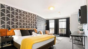 A hotel room with a large bed, a desk, a chair, and a TV. - KozyGuru | Sydney CBD | Charming City Studio (Haymarket)