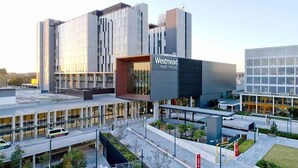 Un edificio moderno con un llamativo letrero que dice 'Westmead Health Precinct', con fachada de vidrio y un diseño contemporáneo y estructurado.