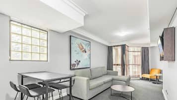 A modern living room with a sofa, a dining table with chairs, a coffee table, and a painting on the wall.