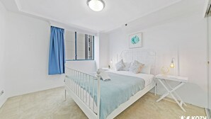 A bedroom with a bed, bedside table, lamp, and a window with curtains.