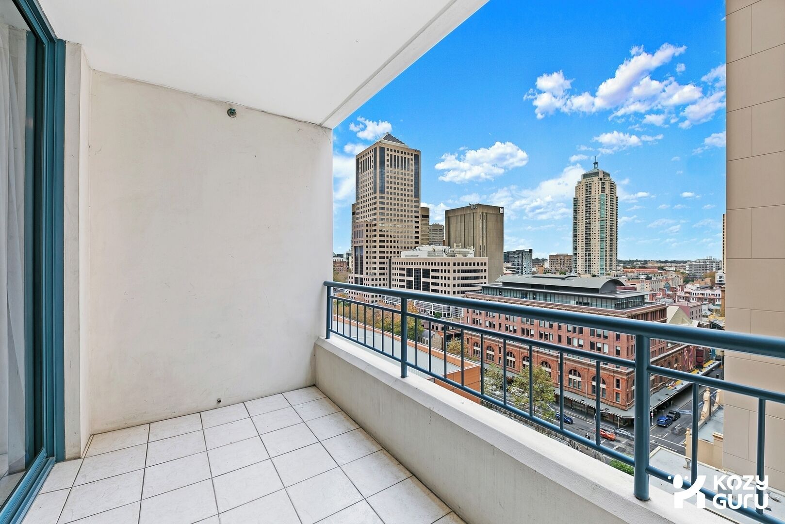 A balcony with a city view, a tiled floor, and a metal railing.