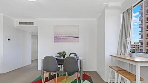A modern dining area with a table, chairs, and a colorful rug.