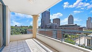 A balcony with a cityscape view, a tiled floor, and a metal railing.