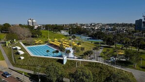 A large swimming pool with multiple lanes, surrounded by a well-maintained lawn and palm trees. - CBD - 2BR in Heart of Sydney, light rail at door (Haymarket)