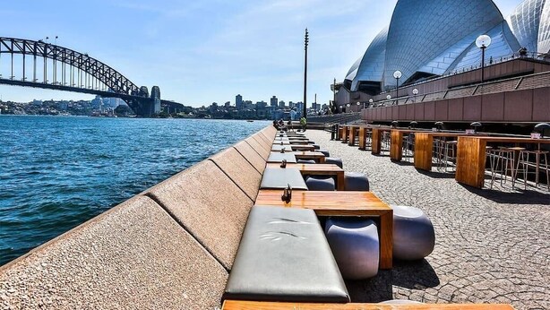 A waterfront promenade with seating, a bridge, and a modern opera house. - CBD - 2BR in Heart of Sydney, light rail at door (Haymarket)