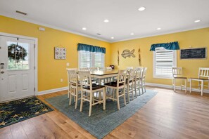 A dining area with a table and chairs, a door, and a window with blinds. - Luxury home w/private pool, walking distance to the beach, eateries and shopping (North Myrtle Beach)
