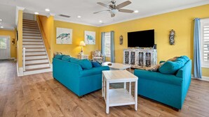 A living room with teal sofas, a white coffee table, and a staircase leading to another level. - Luxury home w/private pool, walking distance to the beach, eateries and shopping (North Myrtle Beach)