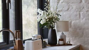 A kitchen counter with a toaster, a vase with white flowers, a lamp, and a jar labeled "RELAX". - Diskin House Mt Pleasant Rd, Eltham. Great for weddings - 2 Kms to Montsalvat. (Eltham)