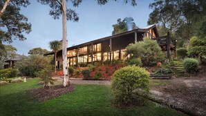 A modern house with a large glass facade, surrounded by a well-maintained garden with various shrubs and a lawn. - Diskin House Mt Pleasant Rd, Eltham. Great for weddings - 2 Kms to Montsalvat. (Eltham)