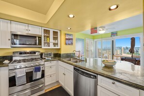 A modern kitchen with stainless steel appliances, a dishwasher, and a large island with a bowl.