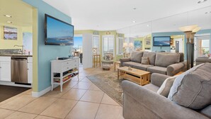 A modern living room with a grey sofa, a coffee table, and a flat-screen TV mounted on the wall. - Oceanfront 2BR/2BA Condo in Oceanside with Amazing Beach Access has AC! (Oceanside)