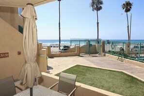 Un espace patio avec vue sur la plage, un détecteur d’incendie et un panneau indiquant le numéro de l’immeble sur le mur.