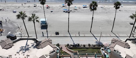 Een hotel aan het strand met een zwembad, palmbomen en uitzicht op de oceaan.