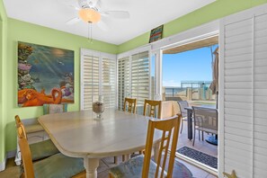 A dining area with a table and chairs, a ceiling fan, and a view of the beach through a sliding glass door. - Oceanfront 2BR/2BA Condo in Oceanside with Amazing Beach Access has AC! (Oceanside)