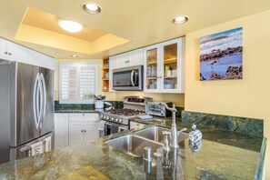 A modern kitchen with stainless steel appliances, a granite countertop, and a view of the outdoors. - Oceanfront 2BR/2BA Condo in Oceanside with Amazing Beach Access has AC! (Oceanside)