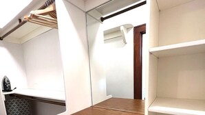 Een inloopkast met een houten aanrechtblad, witte lades en een kledingroede.