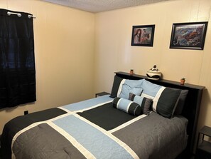 A bedroom with a bed, two nightstands, a black headboard, a black curtain, and two framed pictures on the wall. - Murfreesboro Arkansas walking distance in town 1.9 miles to Crater of Diamond's (Murfreesboro)