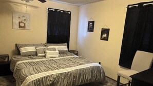 A bedroom with a bed, a chair, a desk, and a wall-mounted shelf. - Murfreesboro Arkansas walking distance in town 1.9 miles to Crater of Diamond's (Murfreesboro)
