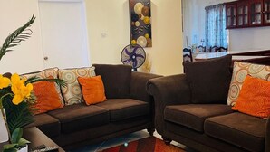 A living room with two sofas, a coffee table, and a wall-mounted fan. - Castle Berry Apartments  (Brighton)