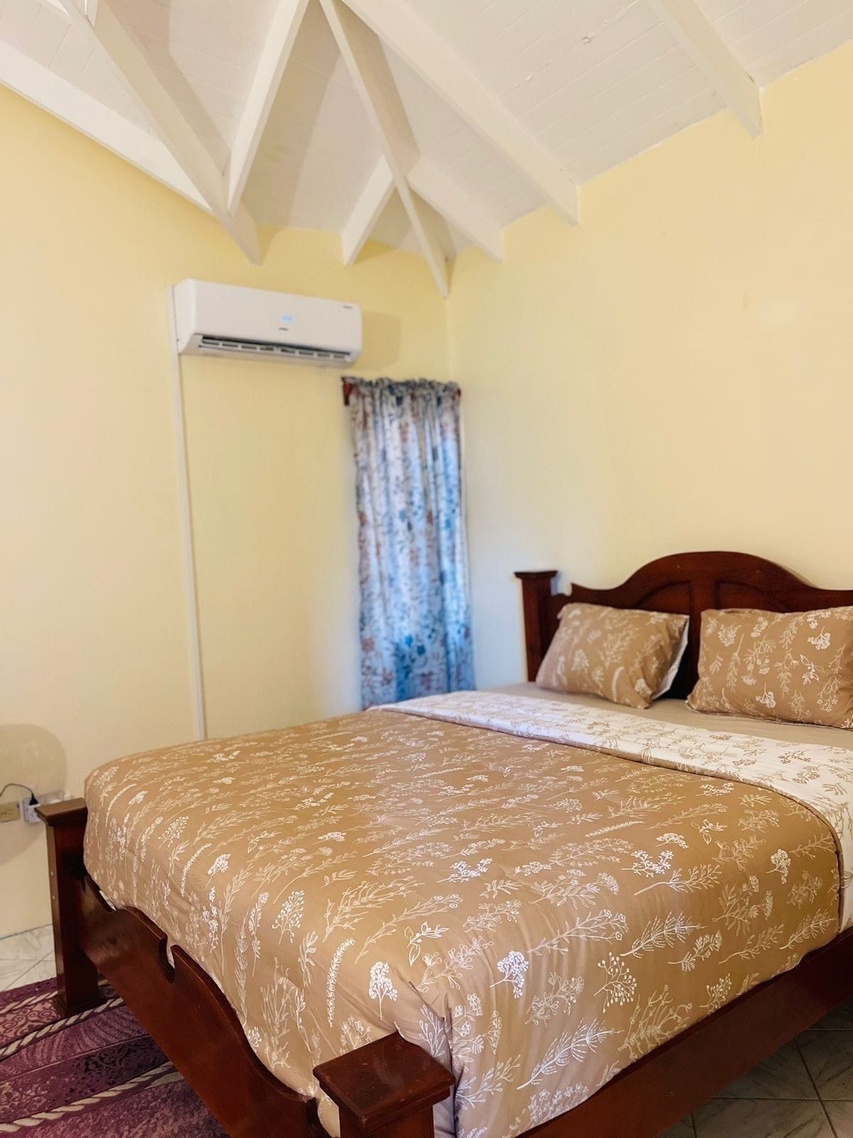 A bedroom with a bed, wooden headboard, and a window with curtains.