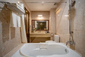 Een moderne badkamer met een ruime badkuip, douche en een wastafel met spiegel.